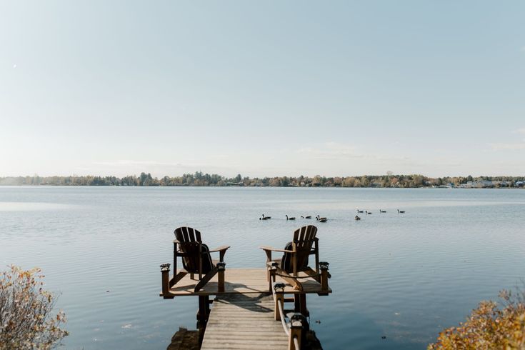 Quai en bois s'étendant dans l'eau calme au crépuscule, éclairé par des lanternes.