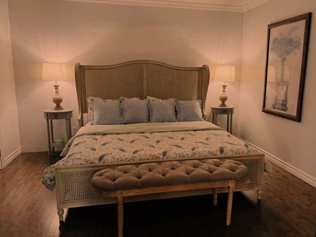 Chambre avec un grand lit, deux tables de chevet avec lampes et des œuvres d'art au mur.