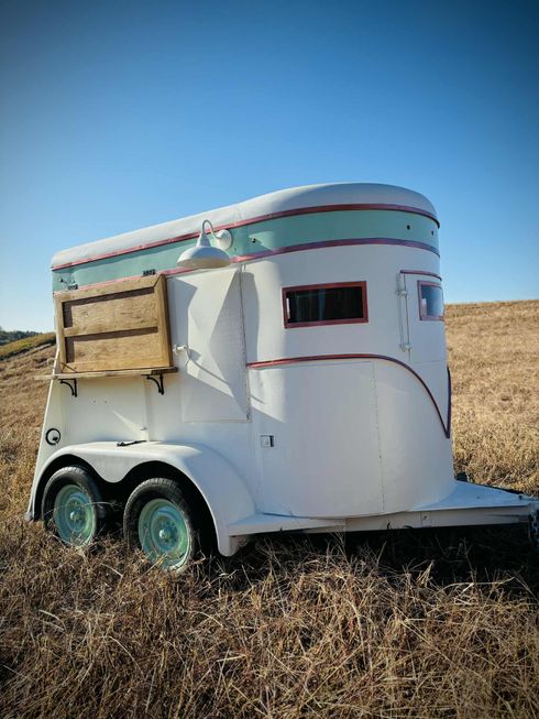 Des gens dans un food truck : des clients mangeant à des tables et commandant de la nourriture à la fenêtre.