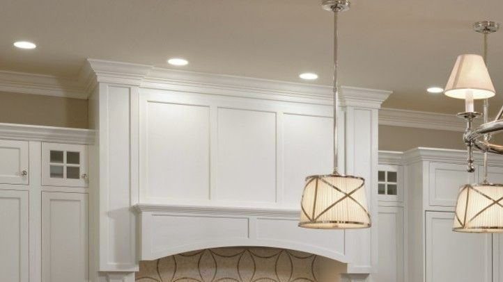 An empty kitchen with white cabinets , a stove , and a sink.