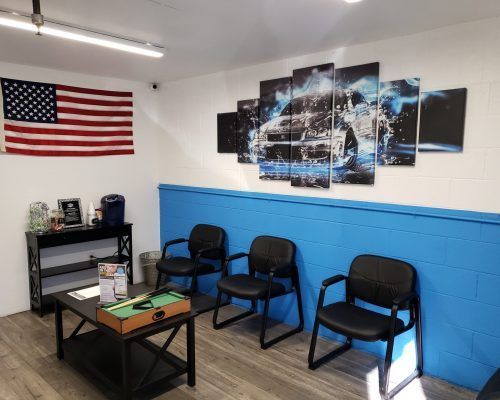 A waiting room with chairs , a table and an american flag on the wall.