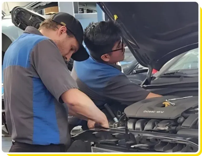 Two men are working on a car with the hood open - Sean's Auto Care