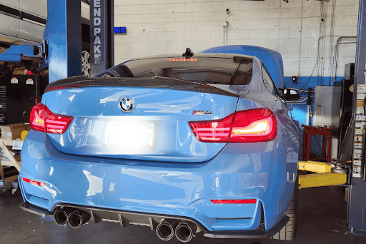 A blue bmw m4 is parked on a lift in a garage - Sean's Auto Care