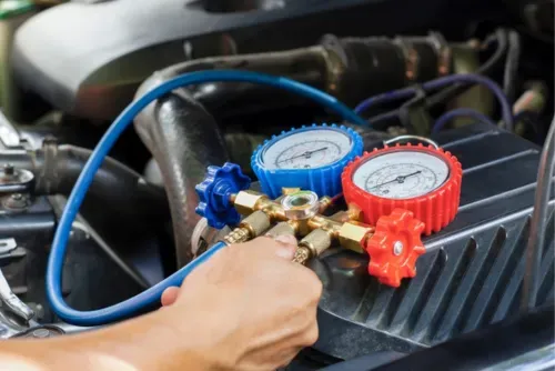 A person is working on an air conditioning system in a car - Sean's Auto Care