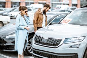A man and a woman are looking at a car in a parking lot - Sean's Auto Care