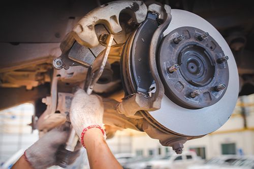 A person is fixing a brake disc on a car with a wrench - Sean's Auto Care