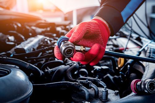 A mechanic is working on the engine of a car - Sean's Auto Care
