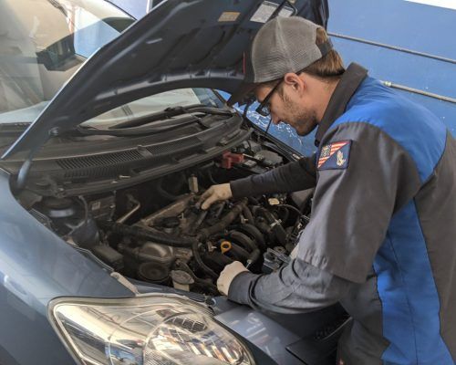 A man is working under the hood of a car - Sean's Auto Care