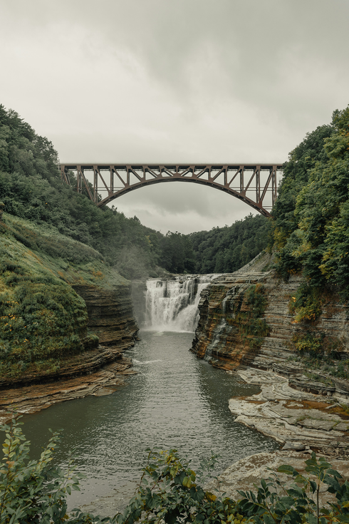 A bridge over a river with a waterfall in the background.