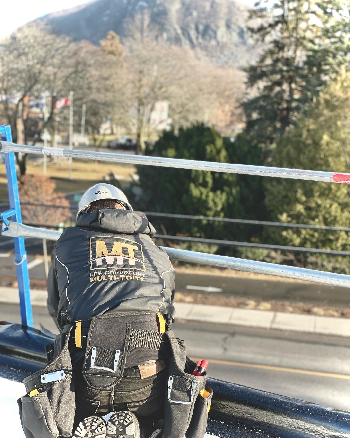 Un homme avec un sac à dos se tient sur un toit avec une montagne en arrière-plan.