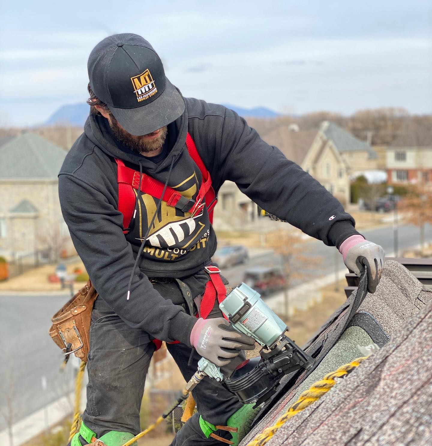 Un homme portant un chapeau noir et un sweat à capuche noir travaille sur un toit.