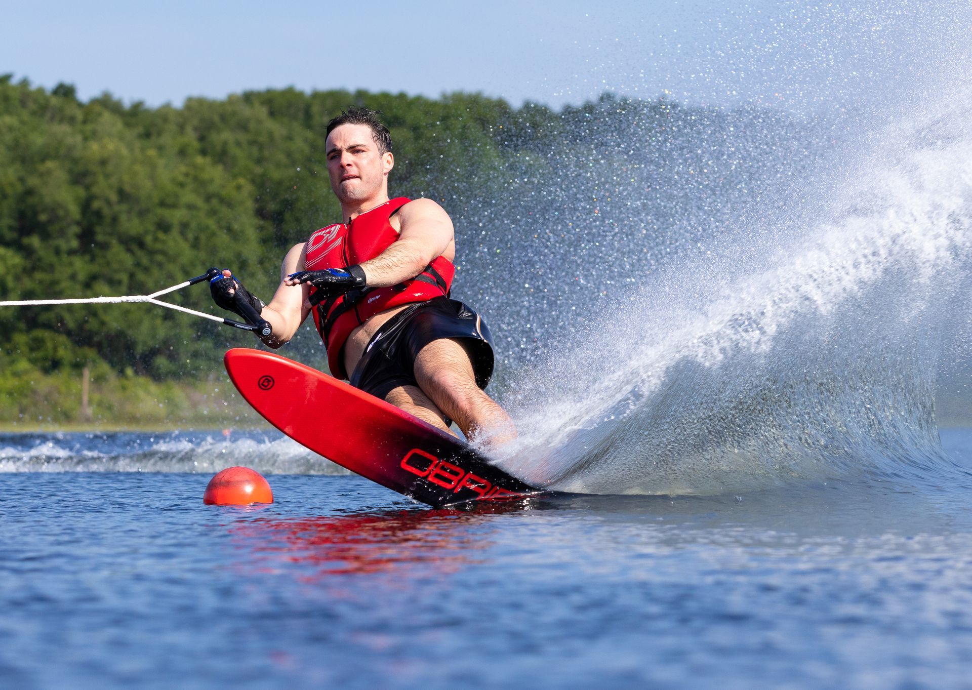 A woman is water skiing on a lake with trees in the background