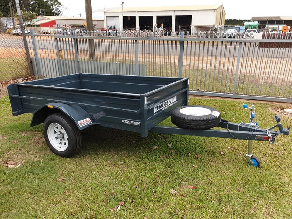 Speed boat on Boat Trailer — Tolga Traders in Tolga, QLD Gray utility trailer parked on green grass. White-rimmed tire. Spare tire mounted on the trailer's frame. — Tolga Traders in Tolga, QLD