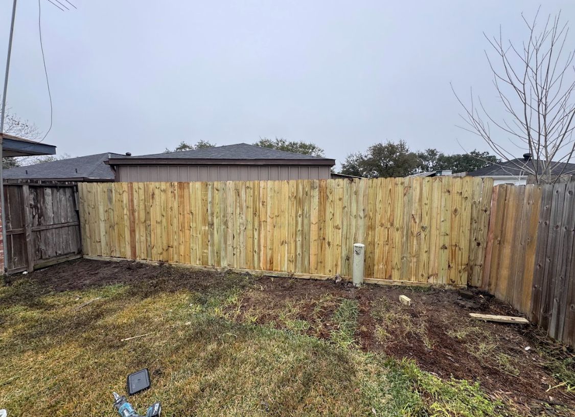 Backyard with a newly installed wooden fence under an overcast sky
