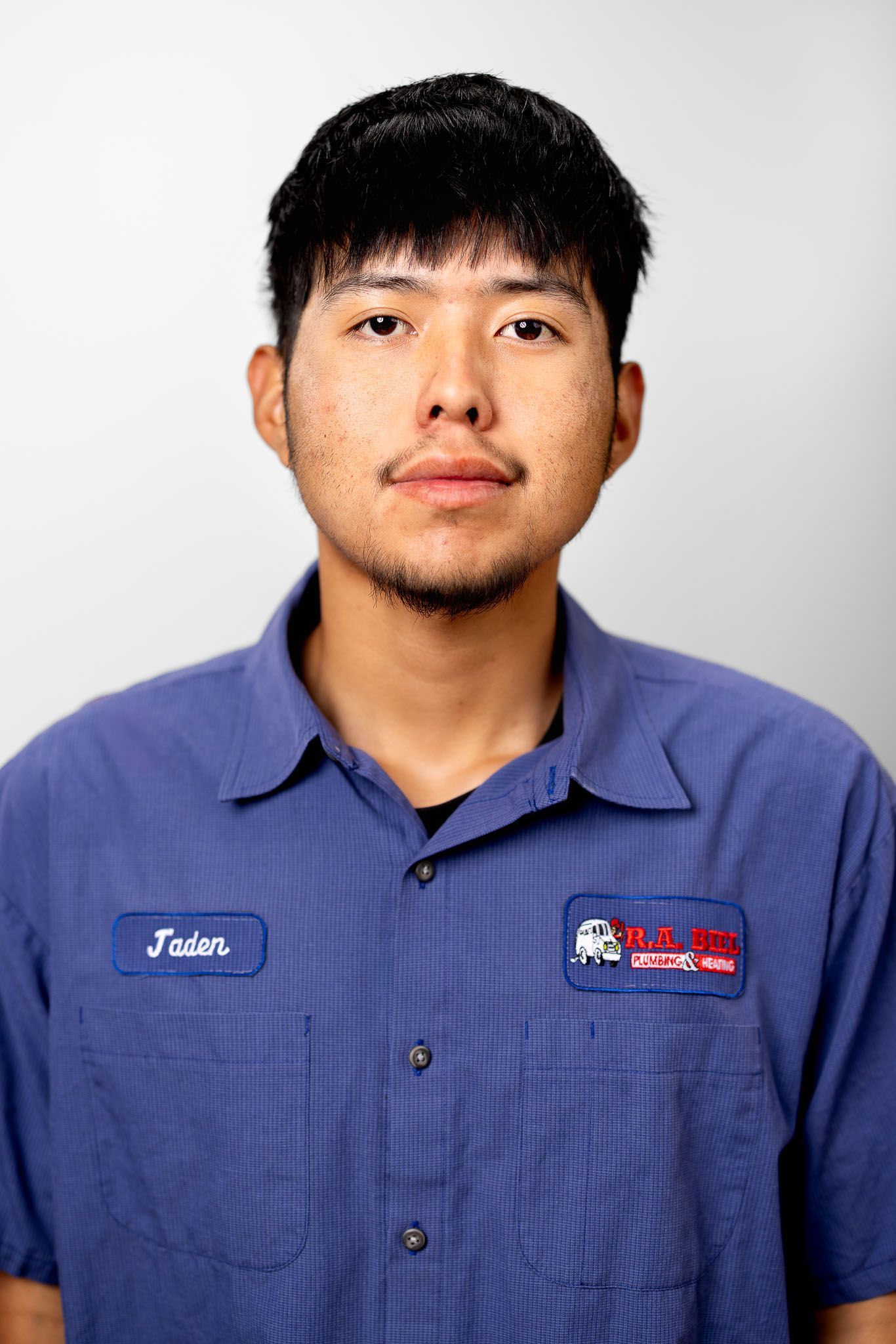 Young man wearing a blue R.A. Biel work shirt, looking directly at the camera for a headshot photo
