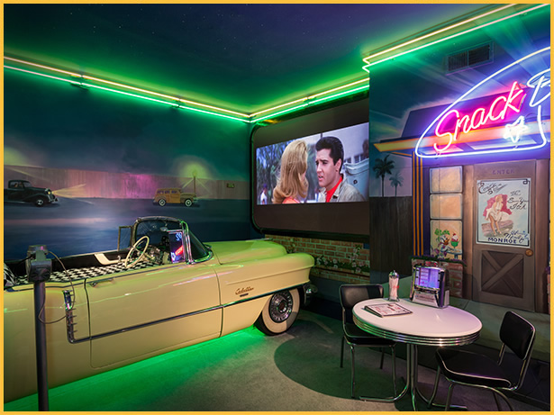 A diner with a car on the floor and a projector screen.