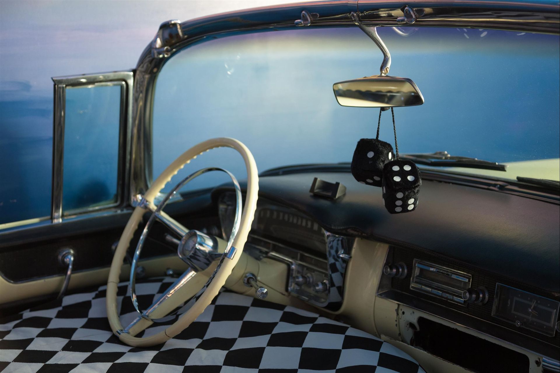 A car with a checkered floor and dice on the dashboard