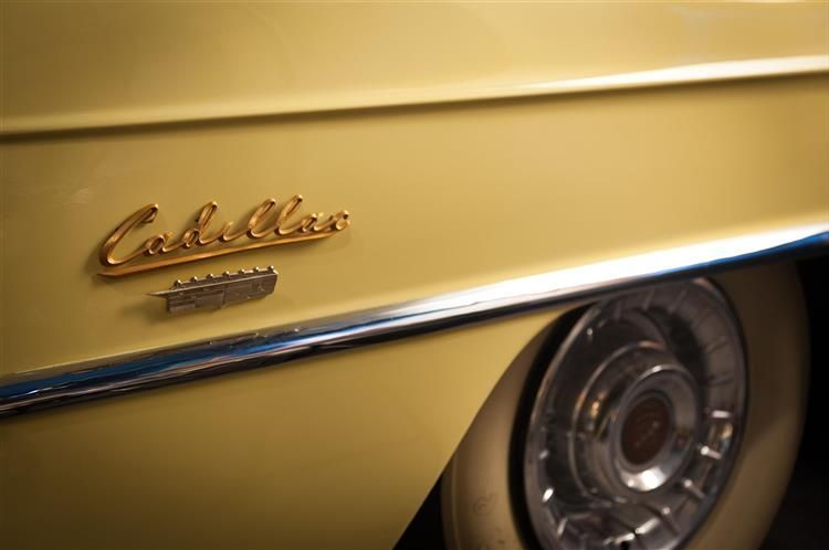 The word cadillac is on the side of a yellow car.