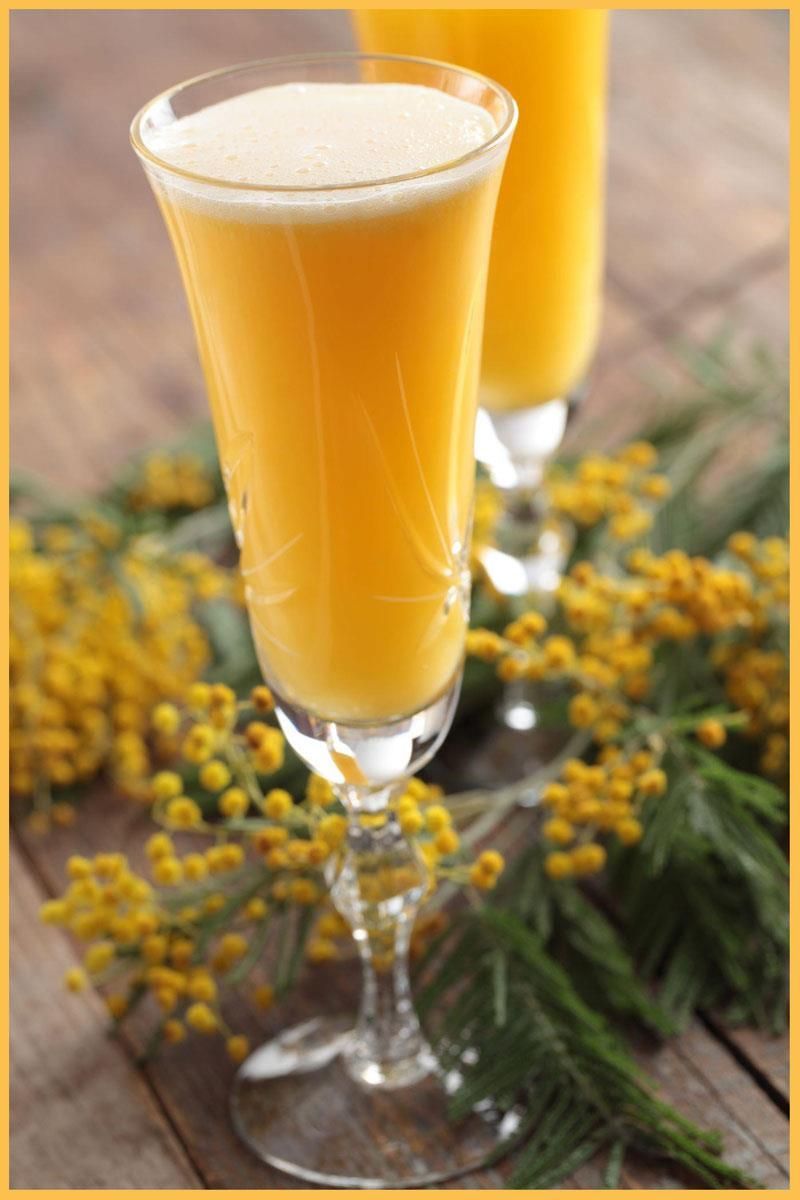 Two glasses of orange juice with yellow flowers in the background