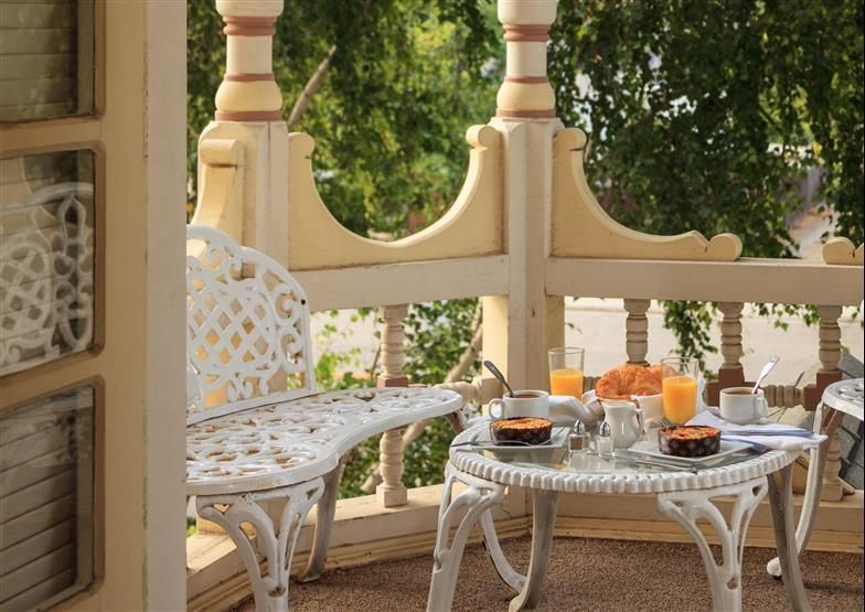 A balcony with a table and a bench with breakfast on it