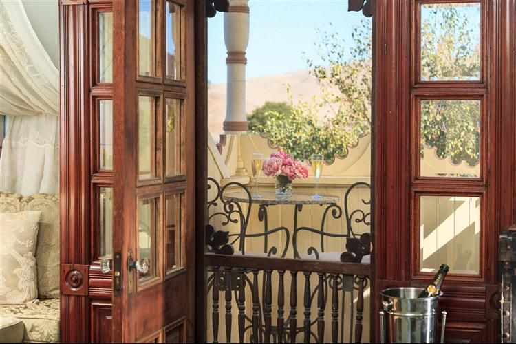 A wooden door open to a balcony with a bucket of champagne on it