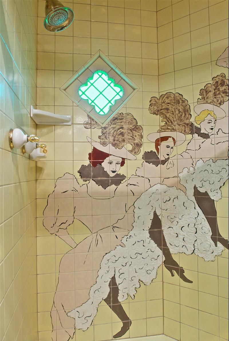 A shower with a painting of three women on the wall