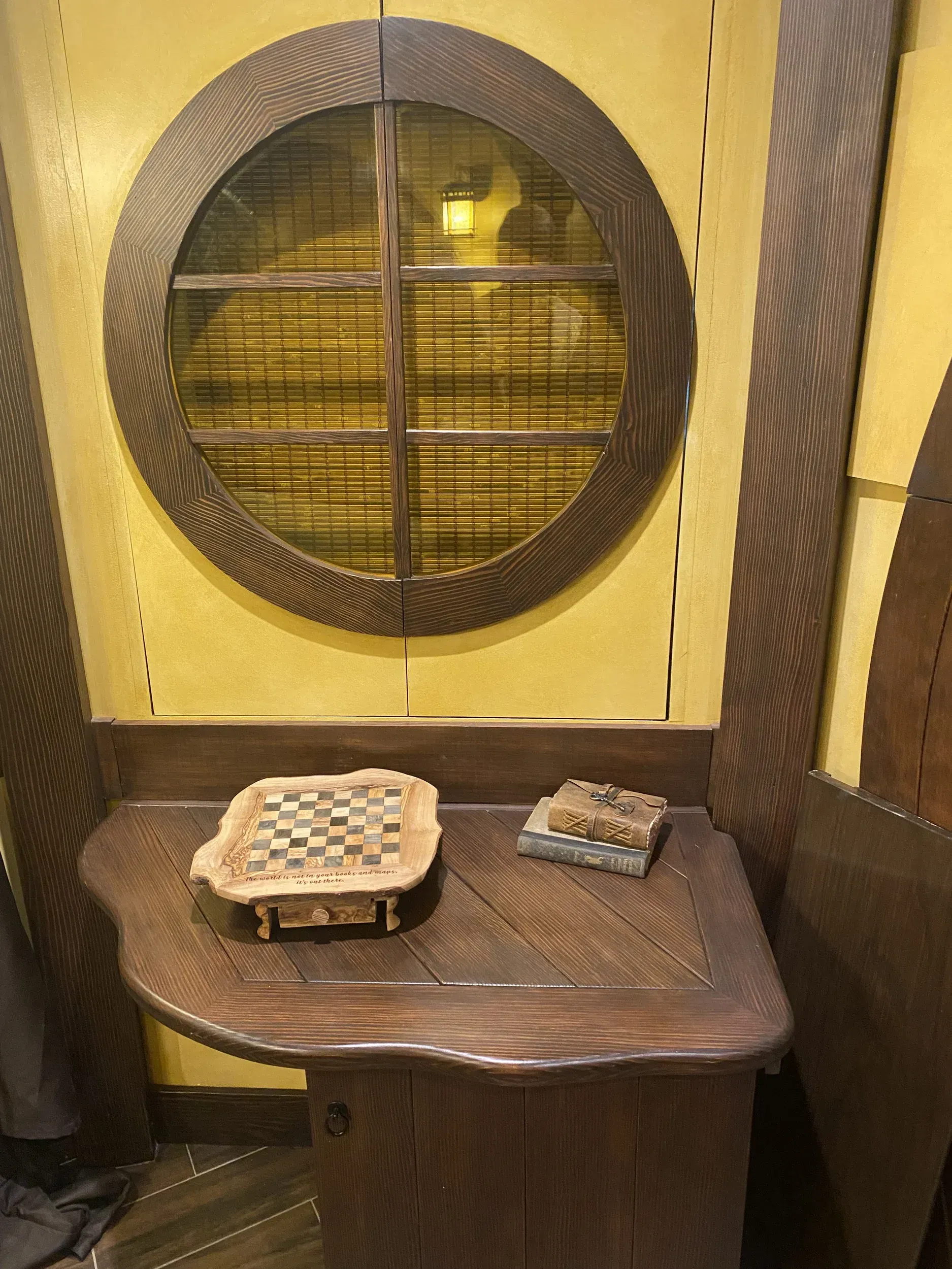 A wooden table with a chess board on it in front of a window.