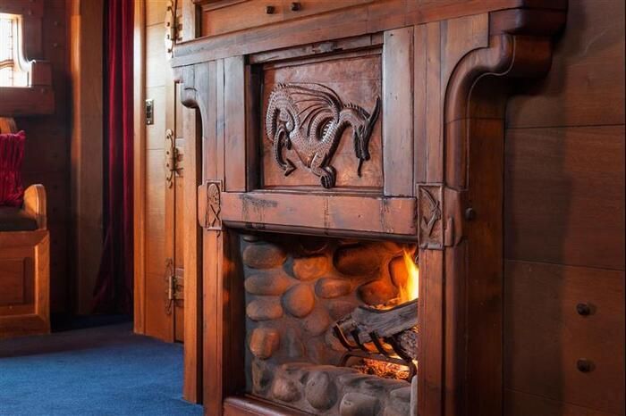 A wooden fireplace with a dragon carved into it is lit up in a living room.