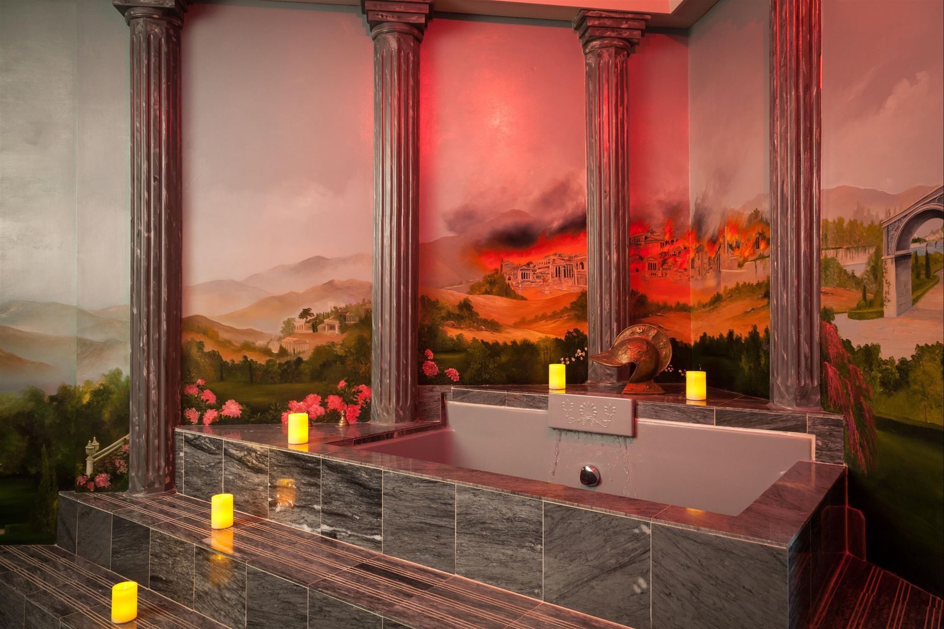 A bathtub in a bathroom with candles and a painting on the wall.