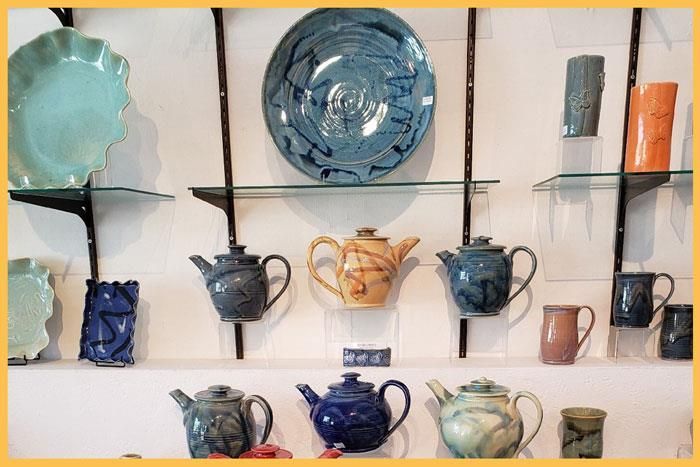 A display of plates , teapots , and cups on a wall.