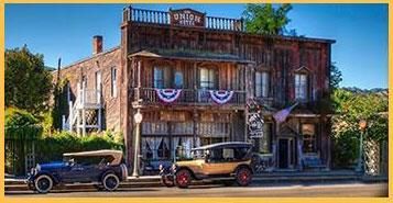 Two old cars are parked in front of a large building.