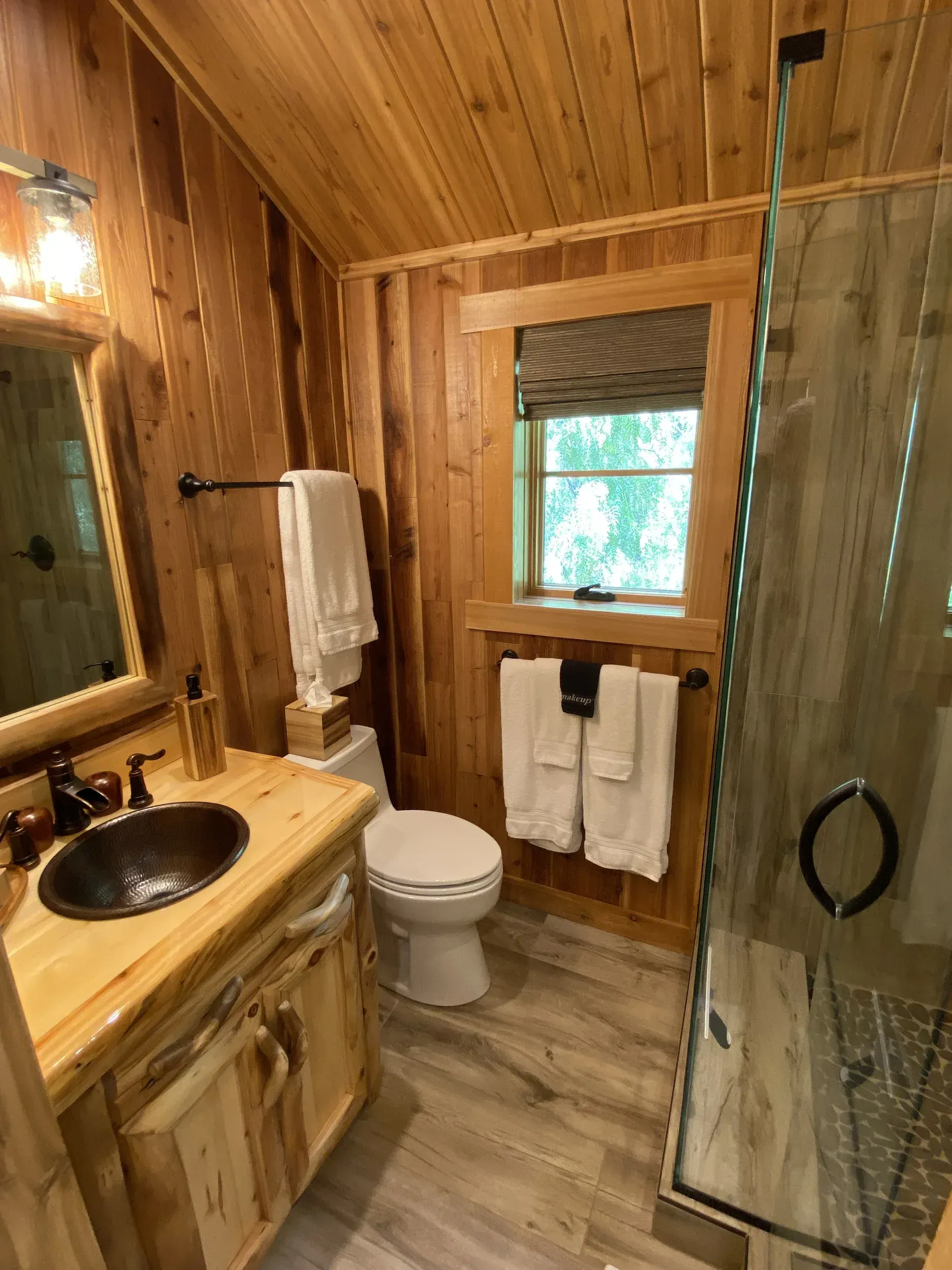 A bathroom with a toilet , sink , mirror and shower.