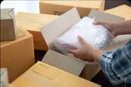 A person is packing a box with bubble wrap.