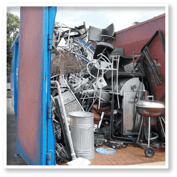 A blue dumpster filled with a lot of trash and junk.