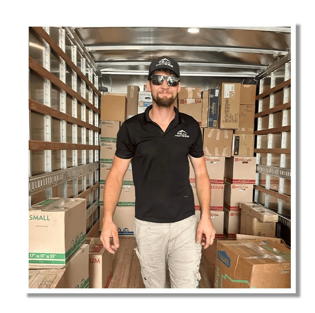 A man is standing in the back of a truck filled with boxes.