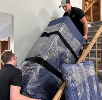 A man is carrying a large box up a set of stairs.