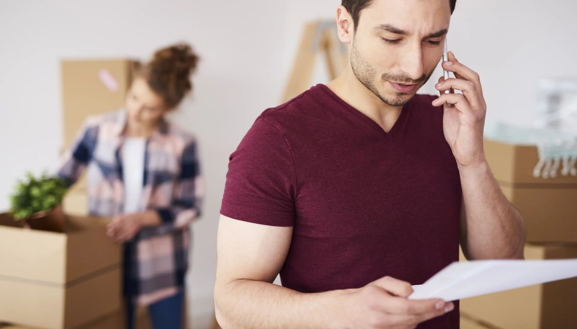 A man is talking on a cell phone while holding a piece of paper.