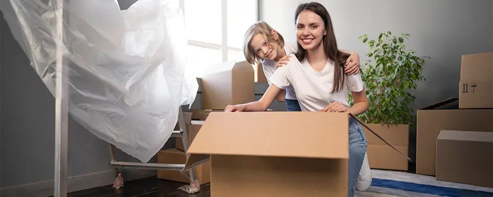 A woman and a child are sitting in a cardboard box.