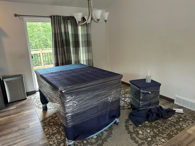 A pool table is wrapped in plastic wrap in a living room.