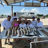 A group of people are standing around a table filled with fish.