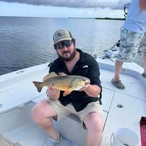 A man is sitting on a boat holding a fish.