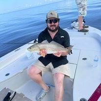 A man is sitting on a boat holding a fish.