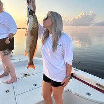 A woman is holding a fish on a boat.