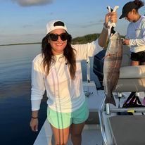 A woman is holding a fish on a boat.