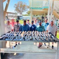 A group of men are standing around a table filled with fish.