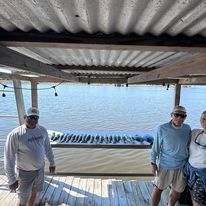 A group of people are standing on a dock overlooking the ocean.