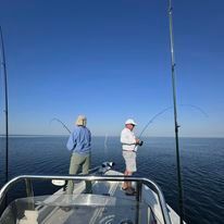 Two men are fishing on a boat in the ocean.