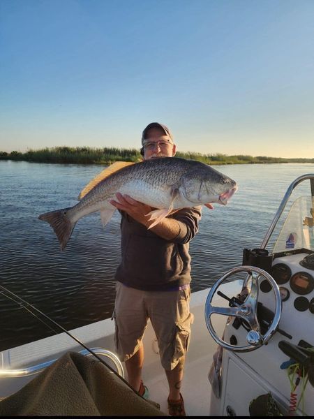 A man is holding a large fish on a boat.