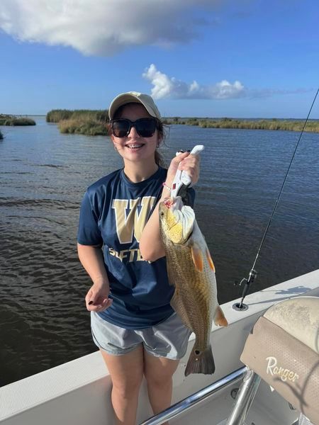 A woman on a boat holding a large fish