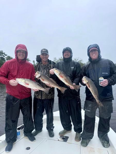 A group of men are standing on a boat holding fish.